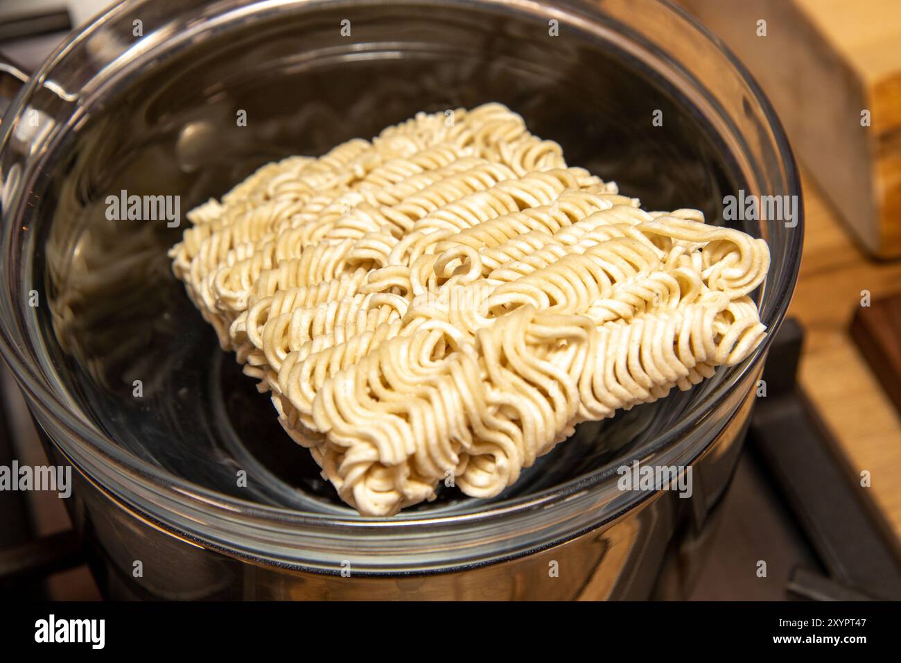 Une casserole contenant un bol d’eau chaude et quelques nouilles séchées prêtes à être cuites Banque D'Images
