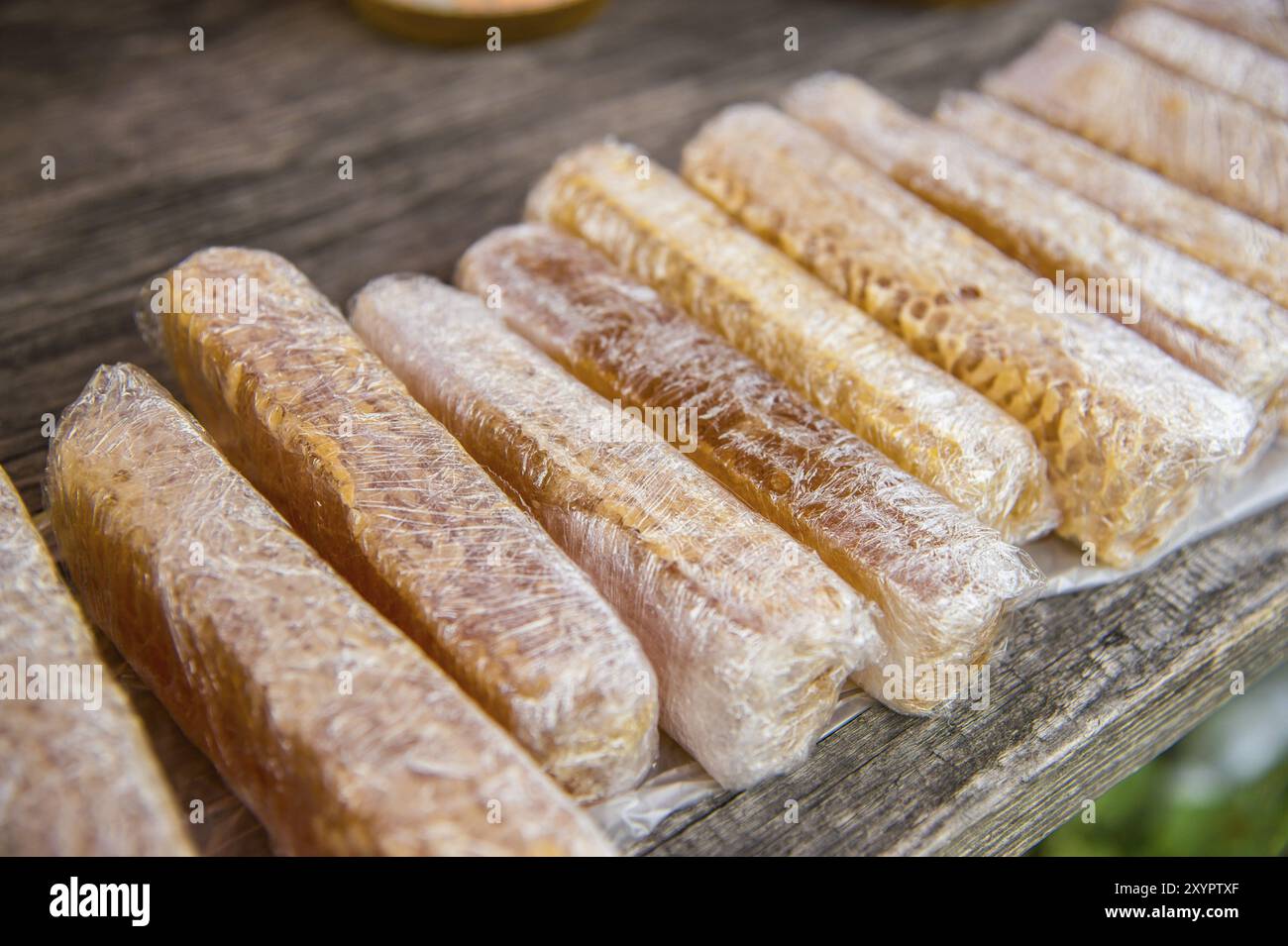 Miel avec des nids d'abeilles emballés dans des enveloppes en plastique sur une table en bois Banque D'Images