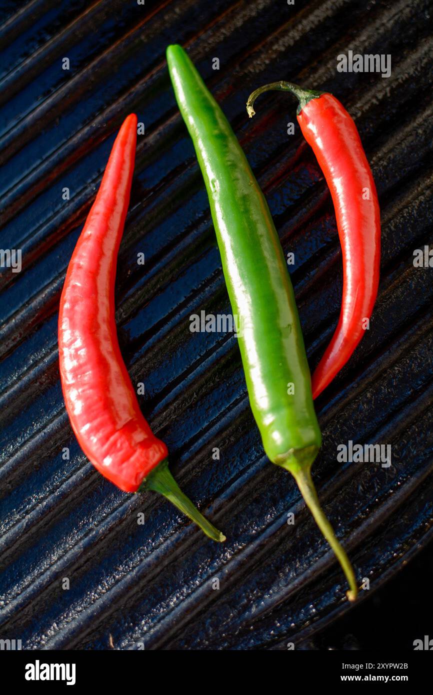Piments rouges et verts sur plaque de cuisson en fonte barbecue Banque D'Images