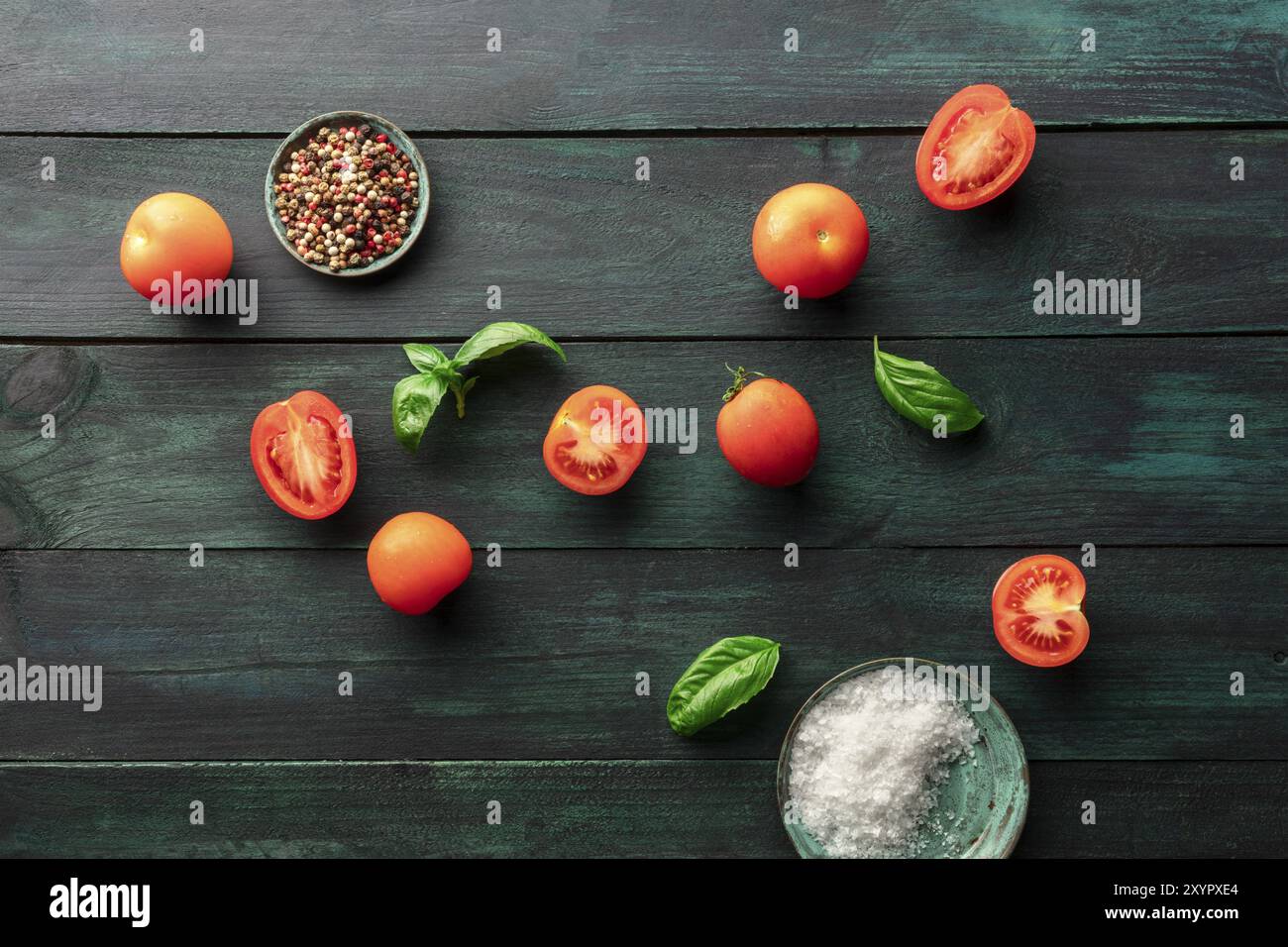 Une photo prise à la verticale de l'héritage biologique les tomates et feuilles de basilic frais sur un fond rustique foncé avec sel, poivre, et un lieu pour le texte Banque D'Images