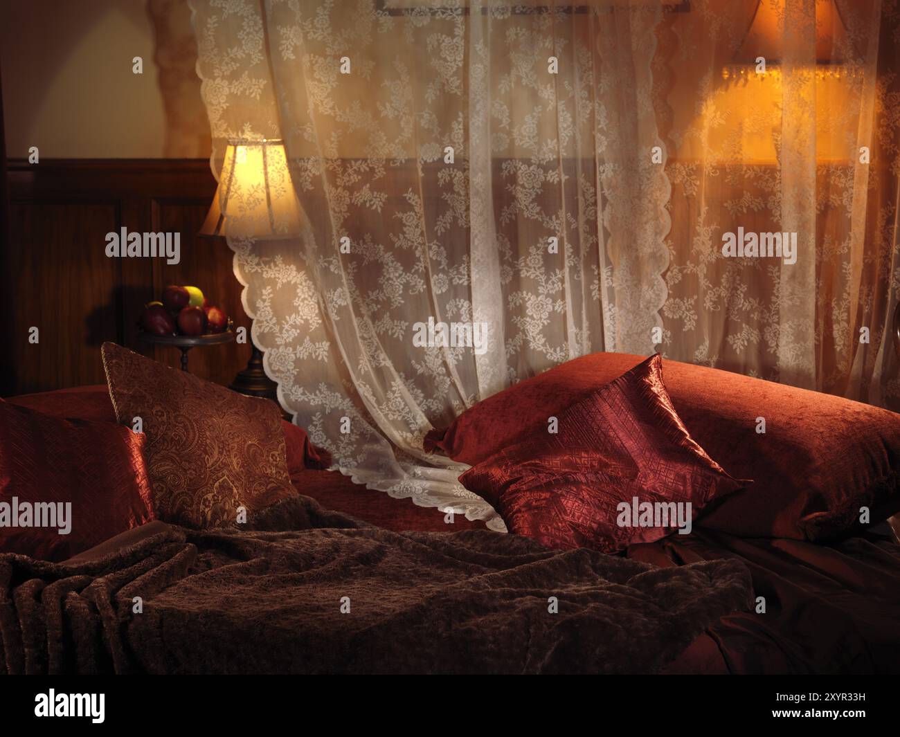 Chambre faiblement éclairée avec lit rouge foncé et deux lampes. Réglages intérieurs Banque D'Images