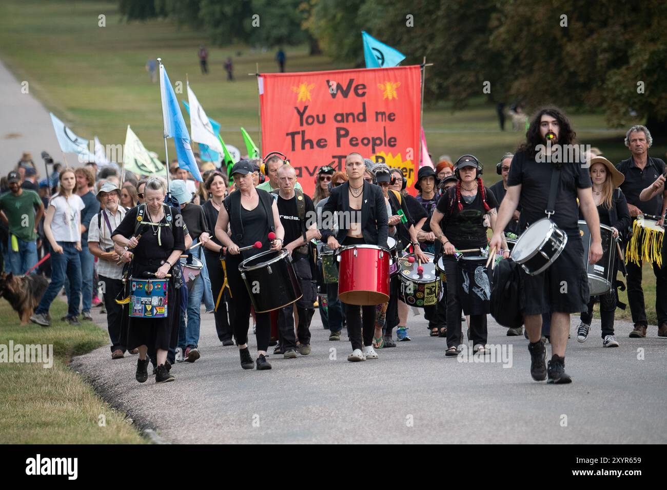 Windsor, Royaume-Uni. 30 août 2024. Extinction Rebellion a organisé une manifestation sur la longue marche avec pour toile de fond le château de Windsor à Windsor, Berkshire ce soir. Les manifestants climatiques de XR portaient des costumes d'affaires et s'habillaient en barons du pétrole, en magnats des médias et en financiers sans visage. Les Oil Slicks, habillés de costumes noirs avec de la peinture de visage noir et blanc, ont réalisé une action théâtrale chorégraphiée dans le but de mettre en évidence le récit XR pour la journée, que le système est brisé. Les rebelles XR campent à Home Park en face du château de Windsor aujourd'hui et pendant le week-end dans le cadre de leur surclassement de trois jours Banque D'Images