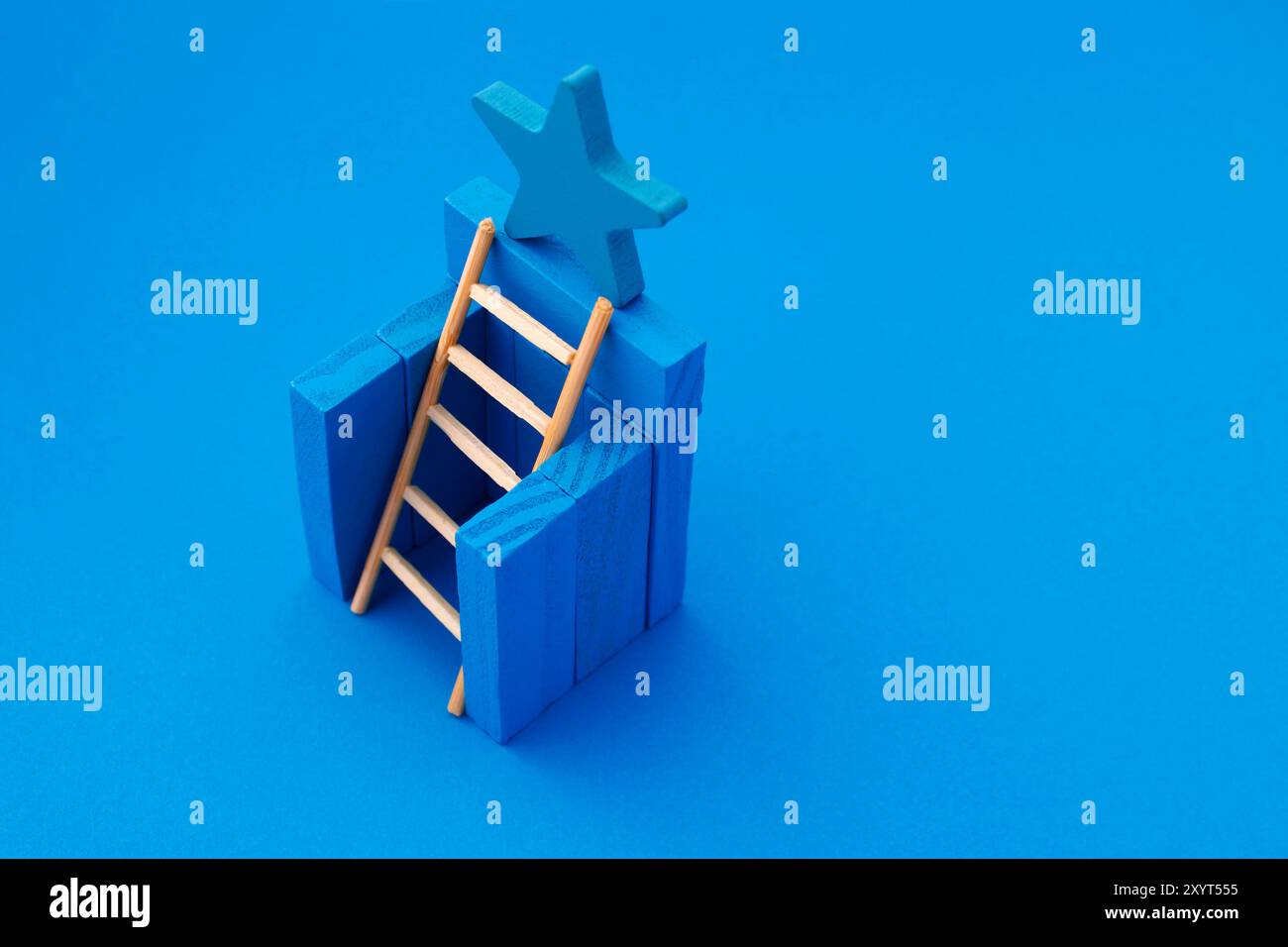 Échelle atteignant une étoile bleue qui est sur un mur Banque D'Images