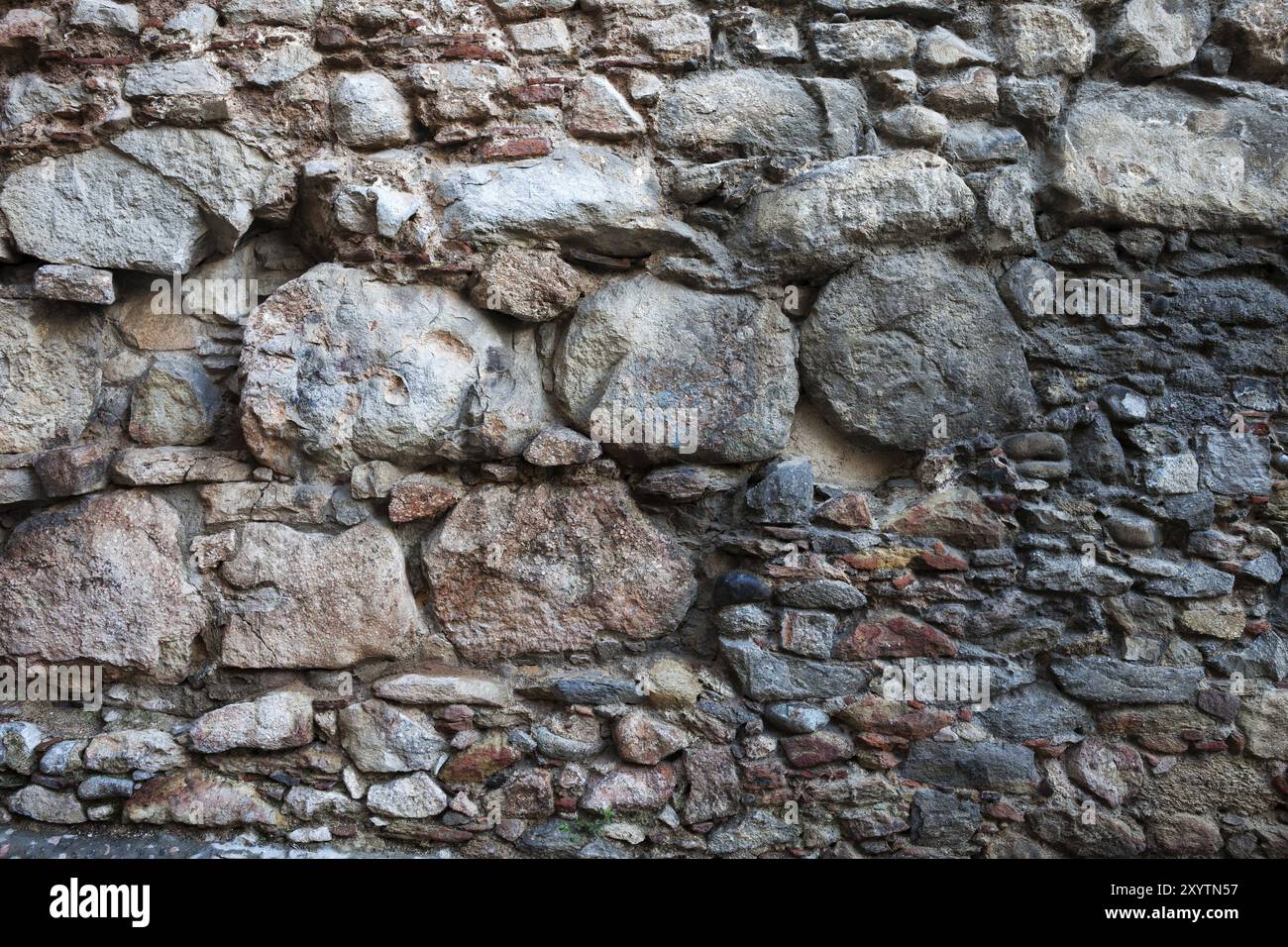 Mur de pierre médiévale ou la texture de fond faite avec de grandes, moyennes et petites tailles des pierres, de la vieille ville de Gérone en Espagne Banque D'Images