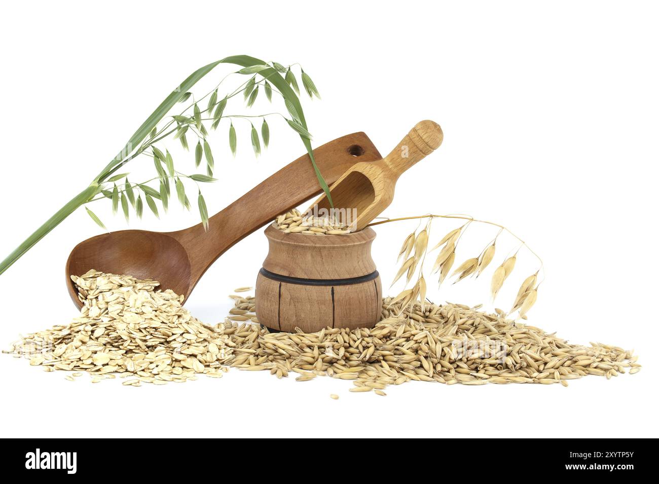 Les gruaux d'avoine roulées et aplaties en flocons dans une cuillère en bois et des grains d'avoine avec des coques ou des feuilles qui se répandent d'un baril en bois isolé sur le backgro blanc Banque D'Images