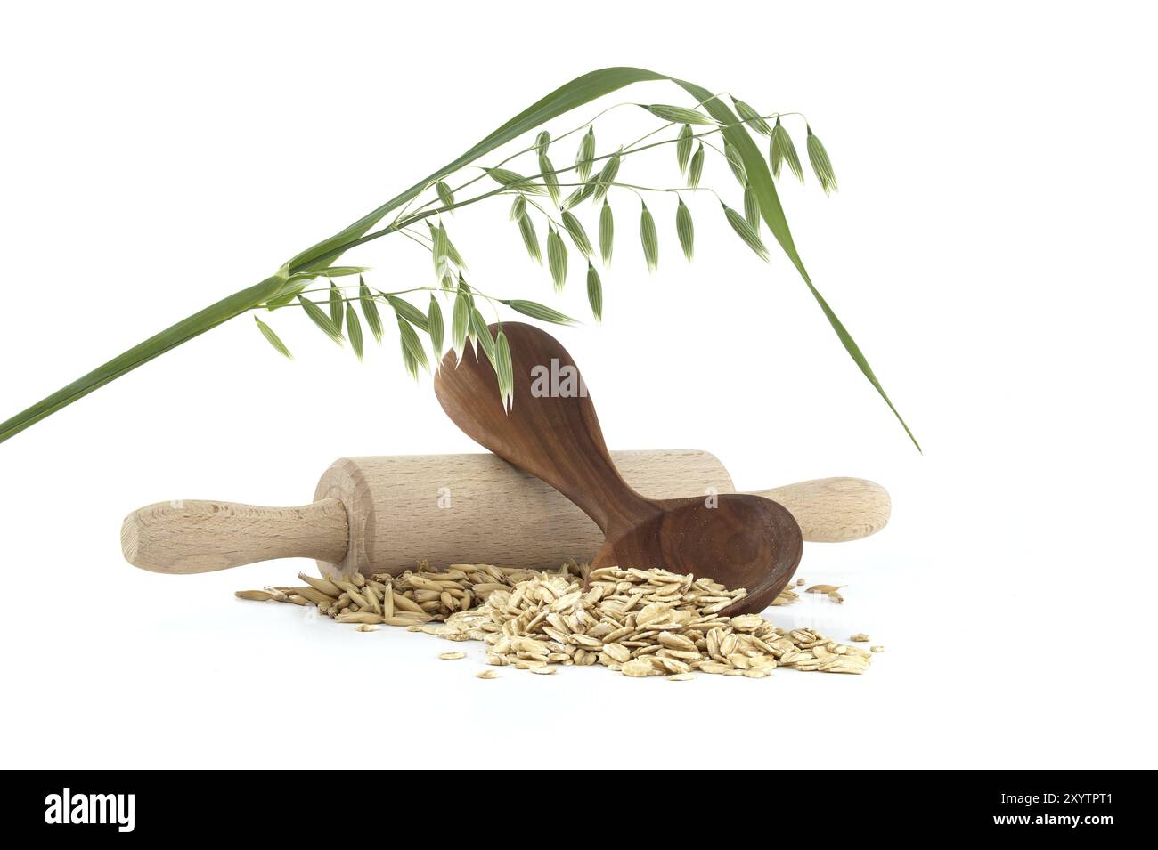 L'avoine groats roulé et aplati en flocons dans une cuillère en bois et des grains d'avoine avec des coques ou des balles près de la broche de bois isolée sur fond blanc Banque D'Images