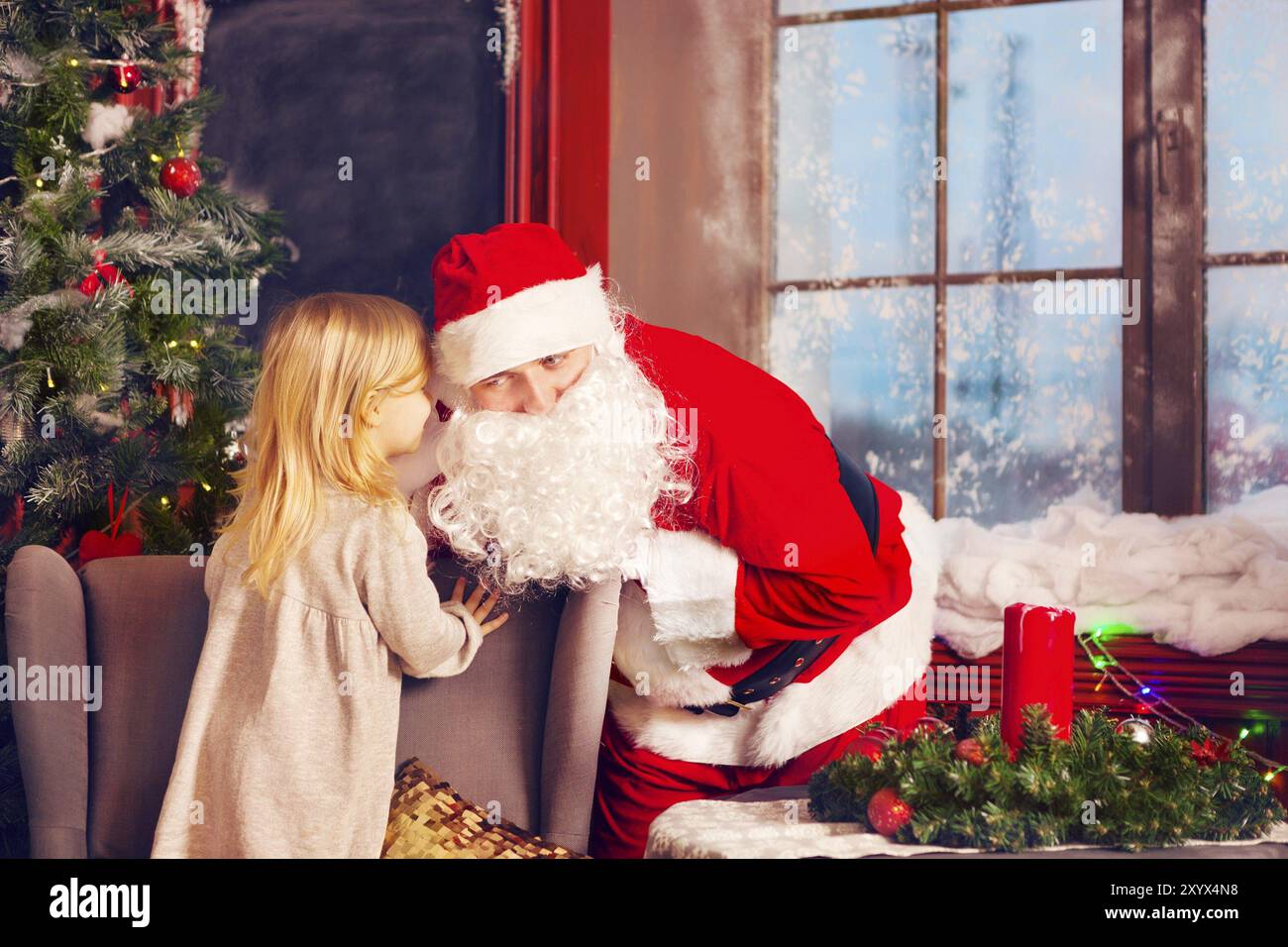 Le Père Noël et la petite fille. Scène de Noël. Fille lui disant vœu de Noël au Père Noël près de l'arbre de Noël Banque D'Images