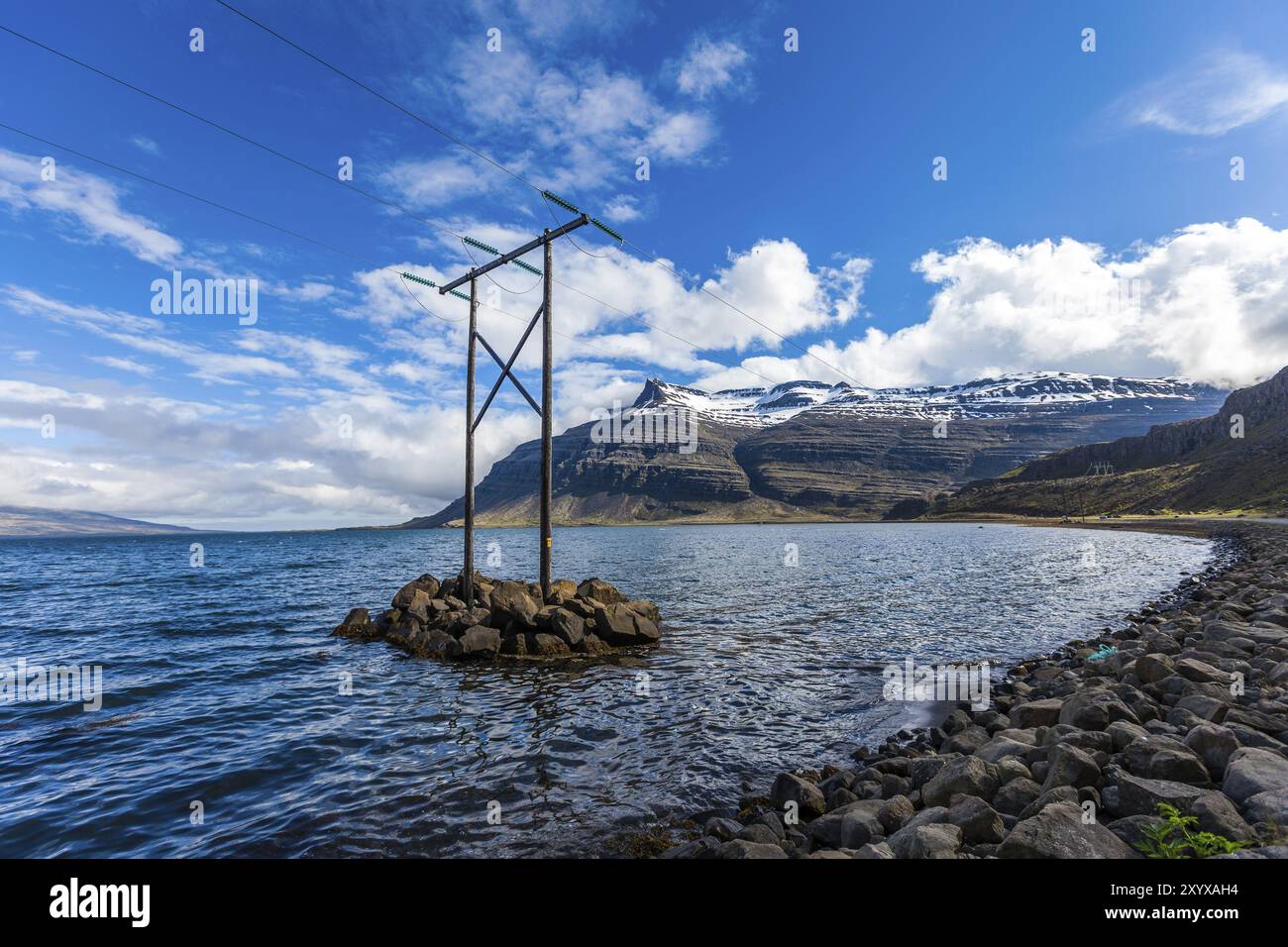 Mât électrique en bois se dresse sur une petite île au milieu d'une baie sur l'Islande Banque D'Images