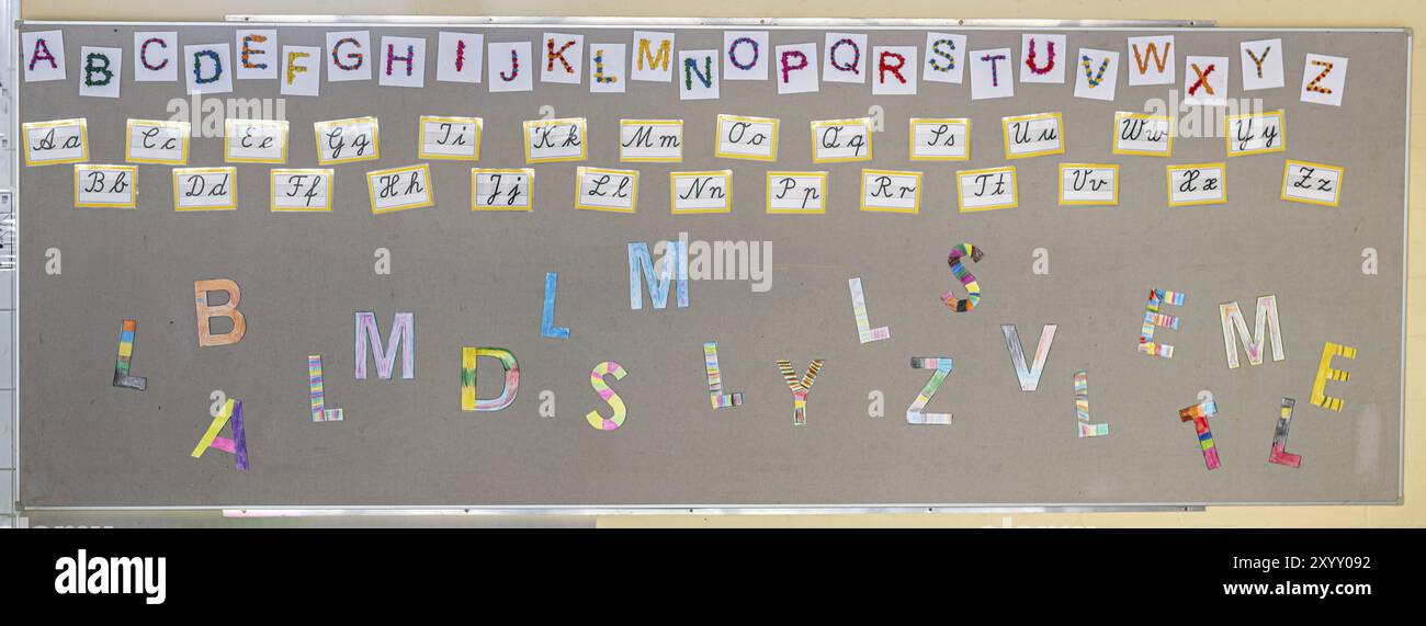 Lettres colorées (alphabet) en caractères d'imprimerie et cursive sur le mur d'une école primaire Banque D'Images