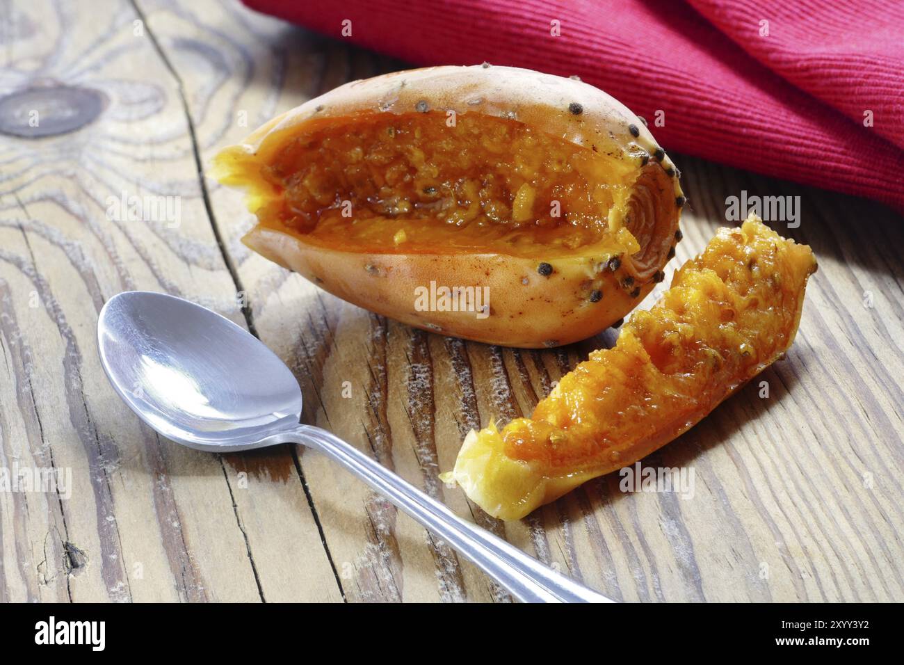 Poire barbarie tranchée et une paix sur une planche de bois rustique, cuillère et serviette rouge Banque D'Images