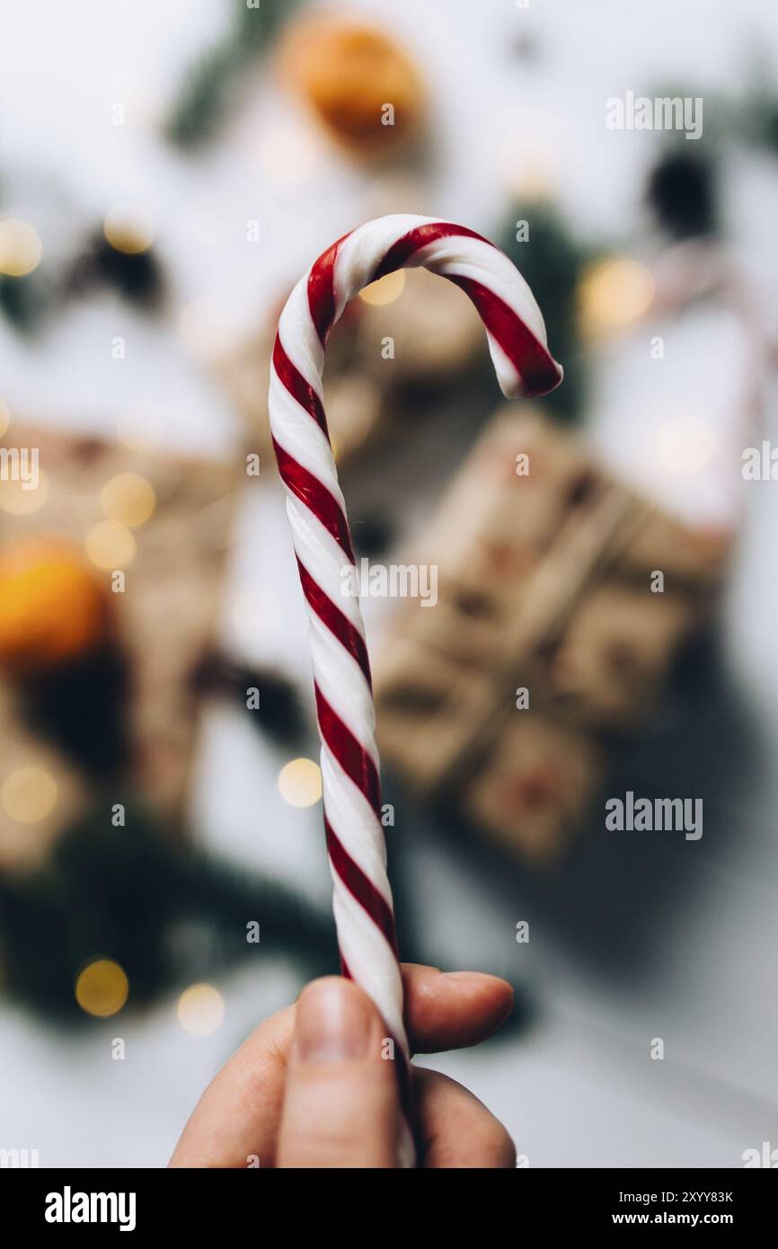 Cadeaux de Noël, mains tient la sucette, mandarine sur fond de bois blanc. Banque D'Images