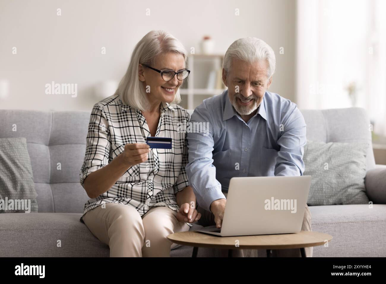 Un couple âgé fait des achats en utilisant un ordinateur portable et une carte de débit Banque D'Images