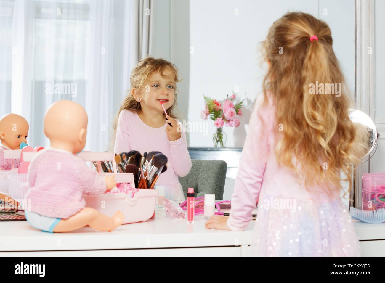 Jeune fille s'amusant derrière la vanité avec le maquillage, regardez le miroir Banque D'Images