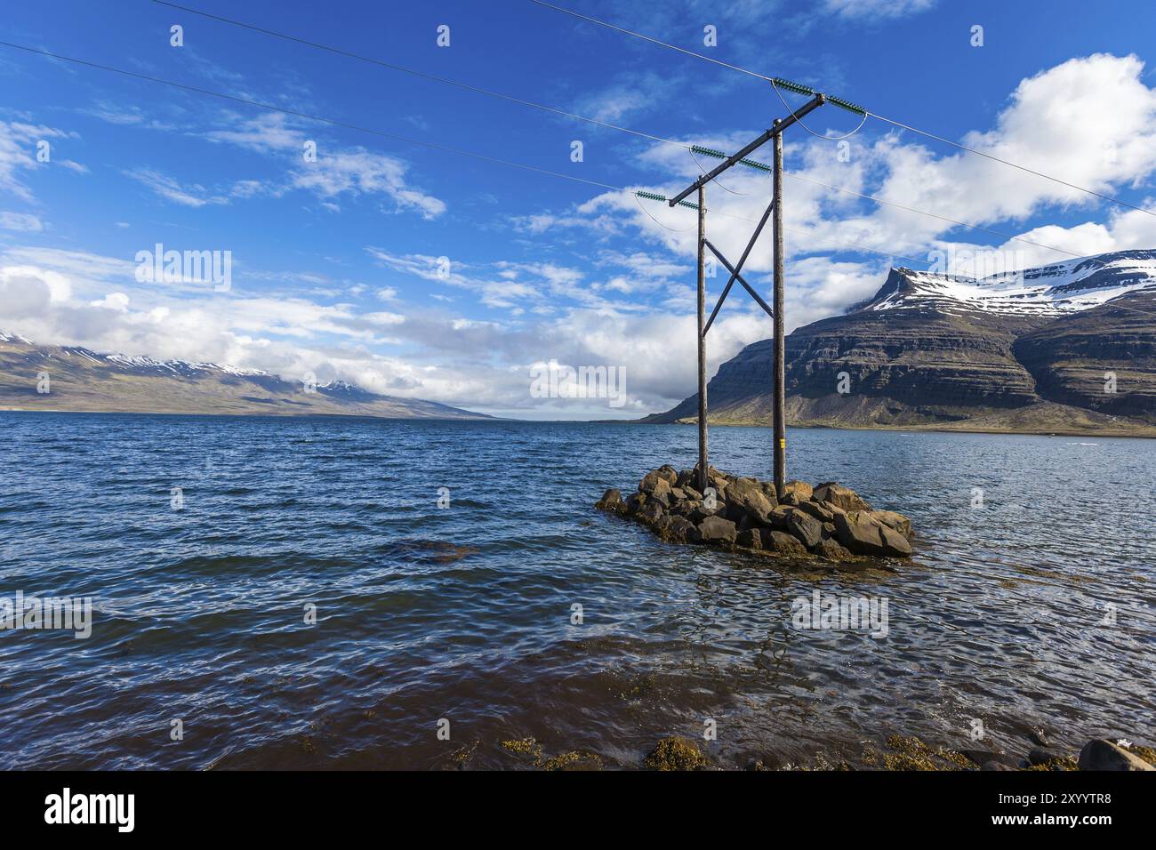 Mât électrique en bois se dresse sur une petite île au milieu d'une baie sur l'Islande Banque D'Images