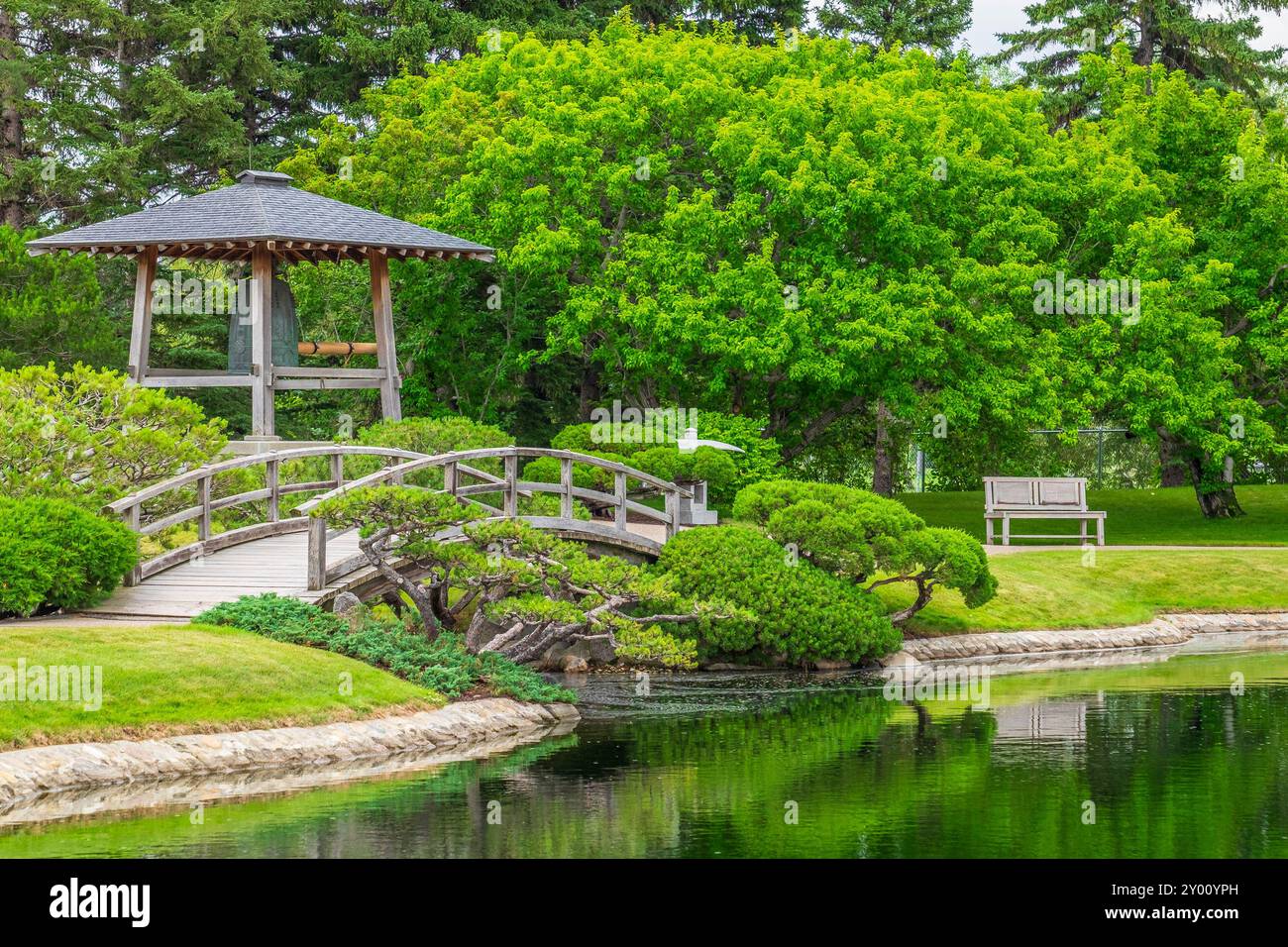 Un pont au-dessus d'une pièce d'eau devant une grande cloche de bronze dans le jardin japonais Nikka Yuko Banque D'Images