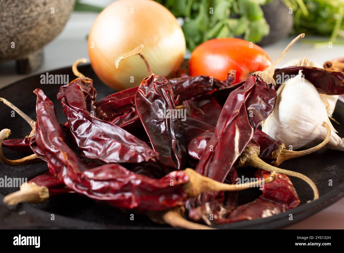 Une vue de piments de guajillo séchés sur un comal, entre autres ingrédients de salsa. Banque D'Images