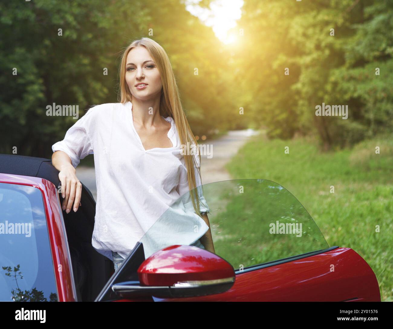 Belle blonde Jeune femme debout près d'une voiture de sport Banque D'Images