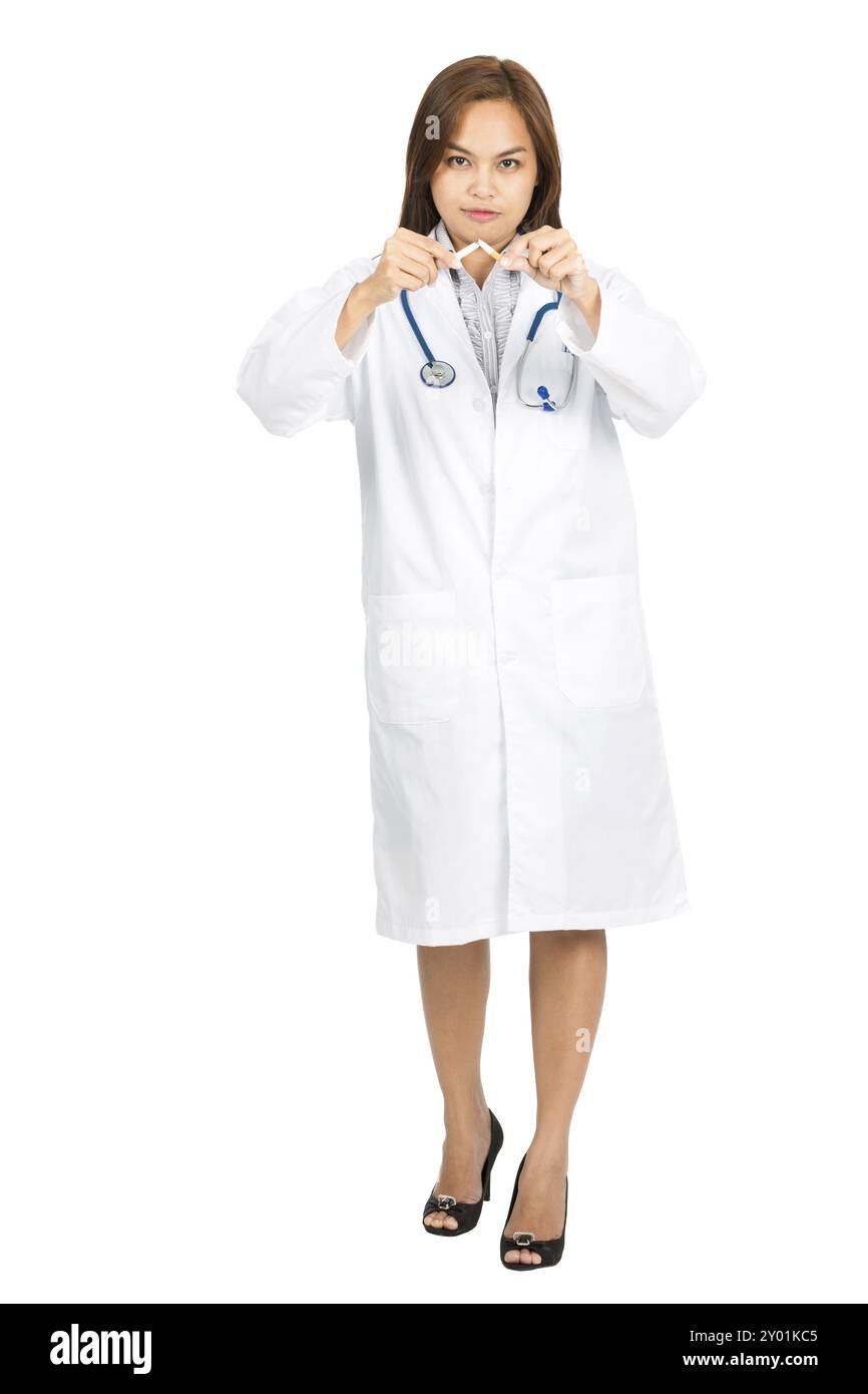 Un médecin asiatique féminin attrayant avec une blouse de laboratoire blanche, stéthoscope regardant la caméra, cassant une cigarette en deux en promouvant arrêter de fumer. Plein Banque D'Images