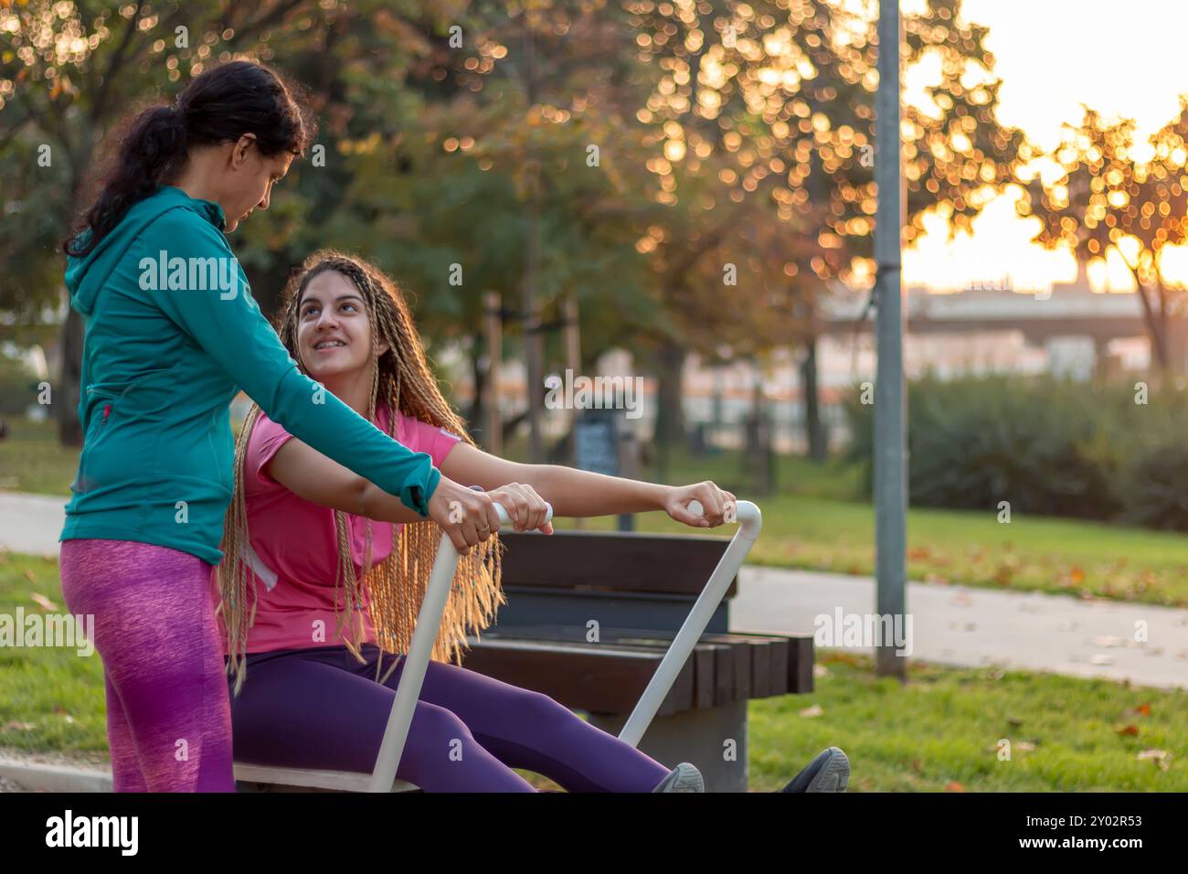 Entraîneur féminin enseignant aux adolescentes à utiliser l'équipement dans le gymnase. Fille communiquant avec le formateur. Entraînement sportif et mode de vie sain. Banque D'Images