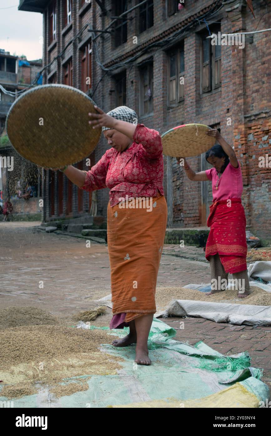 80) deux femmes utilisant des méthodes traditionnelles pour traiter les céréales, Népal Banque D'Images