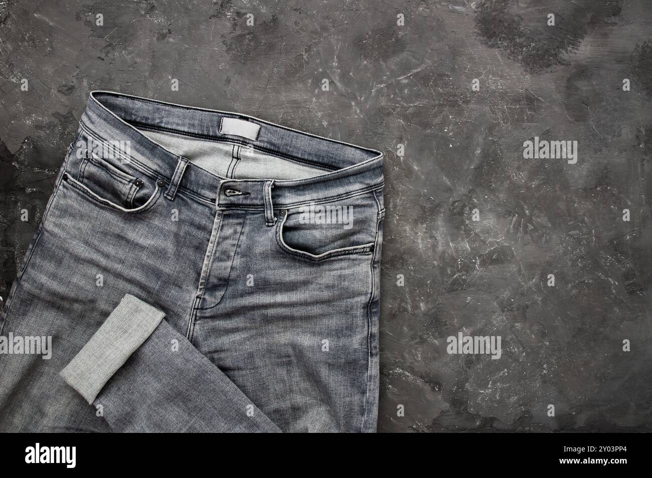 jean denim gris simple, pantalon sur fond rustique de pierre, design de mode Banque D'Images