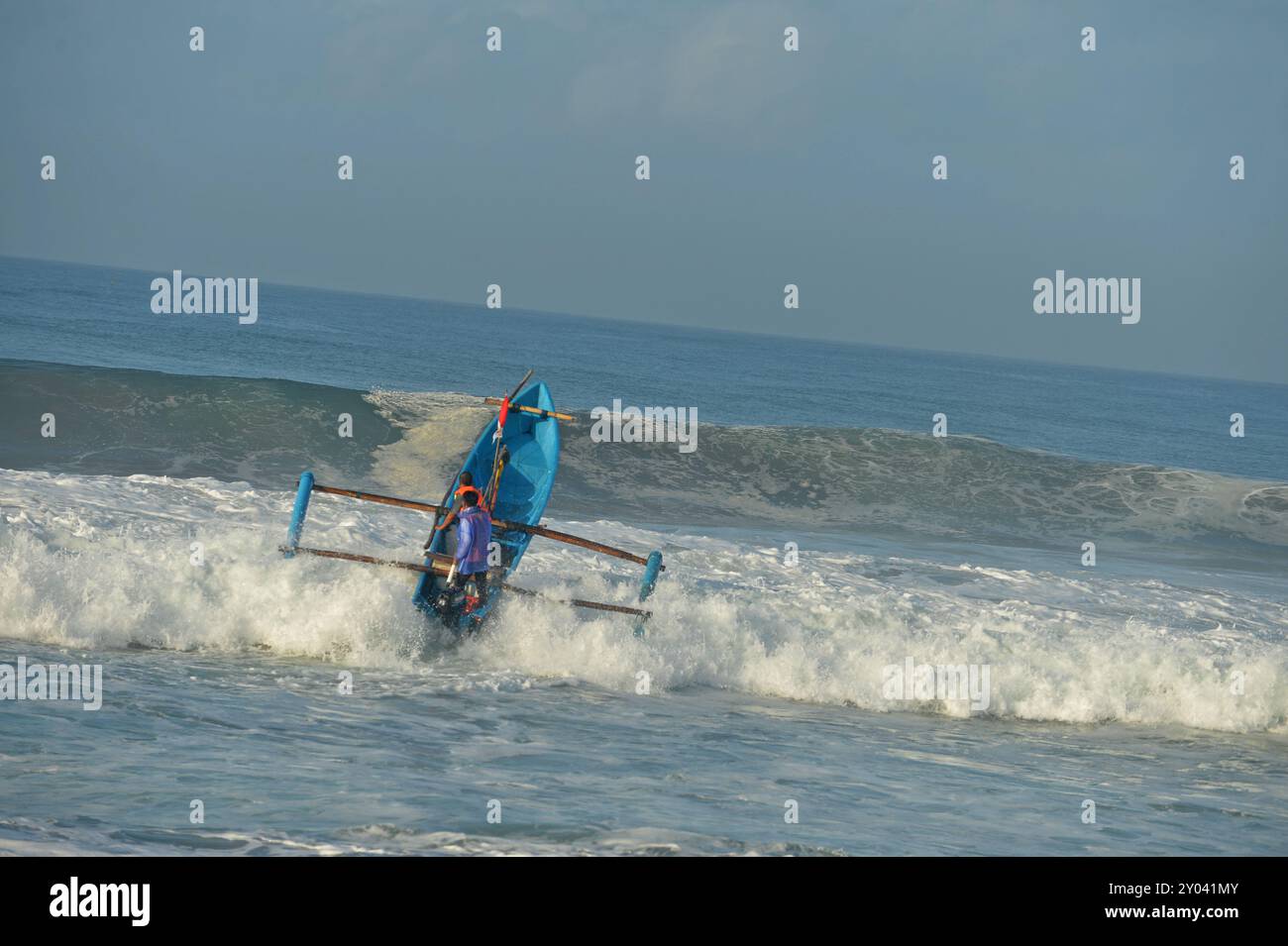 Purworejo, Java central, Indonésie. 30 août 2024. De petits bateaux transportant deux à trois pêcheurs ont bravé de hautes vagues par mauvais temps pour aller pêcher à la plage de Jatimalang sur AÄŸust, 30, 2024. Le mauvais temps et les vents violents n’ont pas découragé les pêcheurs de partir en mer. Ils ont utilisé leur instinct et leurs connaissances pour braver les vagues de huit mètres de haut pour se rendre au milieu de la mer, seuls quelques bateaux de pêche ont osé commencer à pêcher dès l’aube et revenir à midi parce qu’ils ne voulaient pas prendre trop de risques pendant la mauvaise saison météo. (Crédit image : © Dasril Roszandi/ZUMA Press Wire) EDITORIAL Banque D'Images