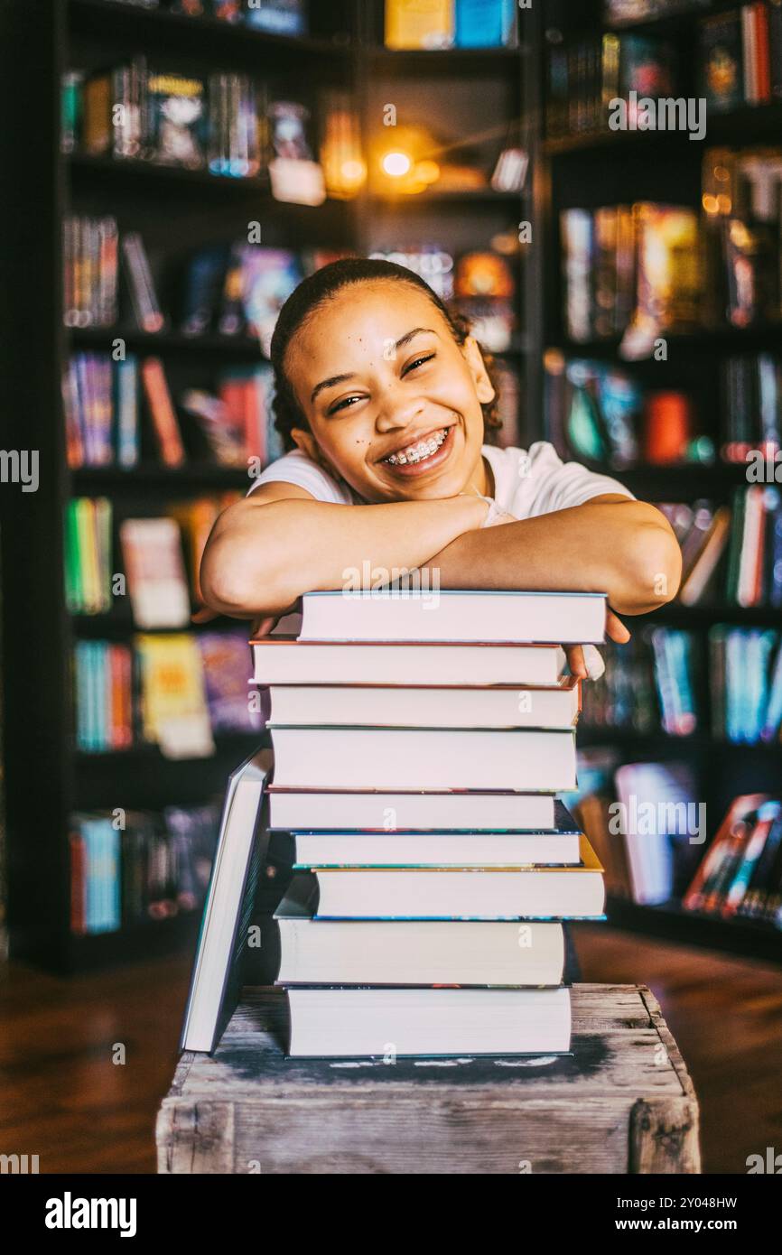 Portrait d'une jeune femme heureuse appuyée sur une pile de livres en librairie Banque D'Images