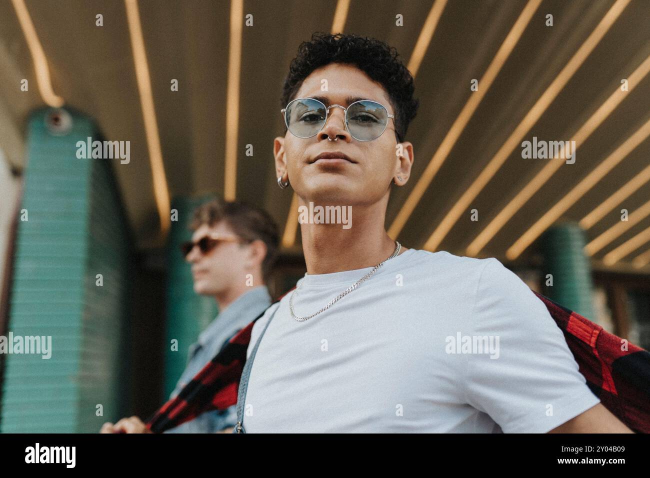 Portrait bas angle de jeune homme à la mode dans des lunettes de soleil et nez percé Banque D'Images