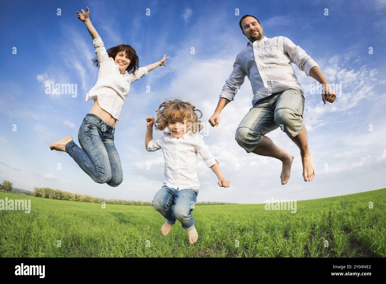 Happy active family jumping in green field. Concept de vacances d'été Banque D'Images Happy active family jumping in green field. Concept de vacances d'été Banque D'Images
