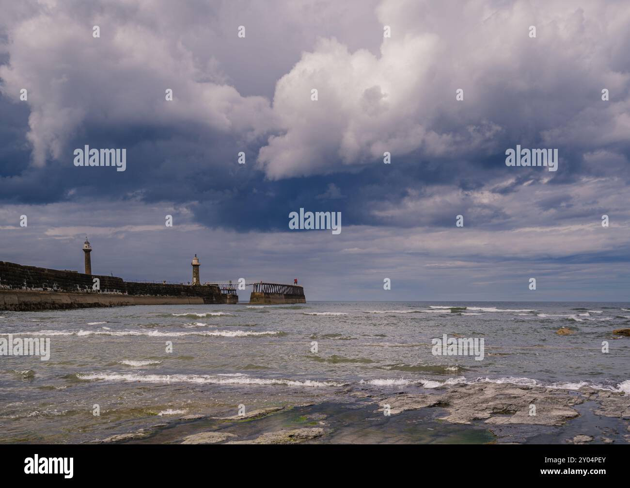 Whitby East Pier sous un ciel couvert et turbulent. Banque D'Images