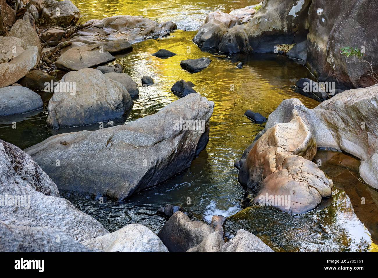 Petite crique de jaune clair et eaux coulant à travers les rochers des montagnes du Minas Gerais Banque D'Images