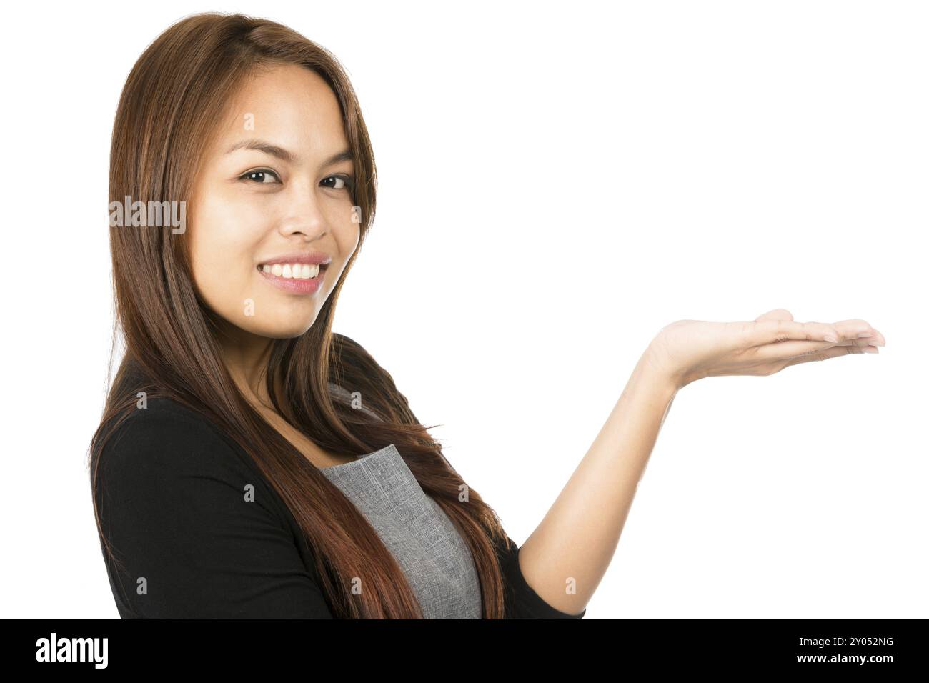 Portrait de côté d'adorable femme asiatique en gris, pull noir, yeux à la caméra tenant la main à plat mettant en vedette le produit inséré imaginaire sur la paume ouverte. Banque D'Images