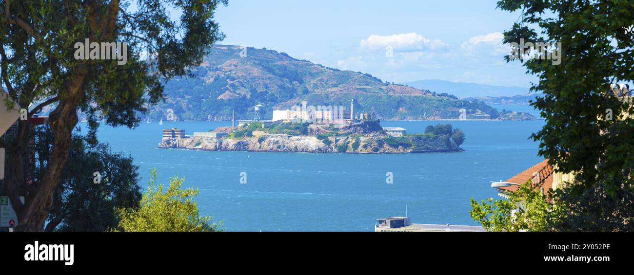 Grand téléobjectif panoramique du pénitencier fédéral d'Alcatraz et de l'île au milieu de la baie de San Francisco encadrée par des arbres de grand angle les jours ensoleillés Banque D'Images