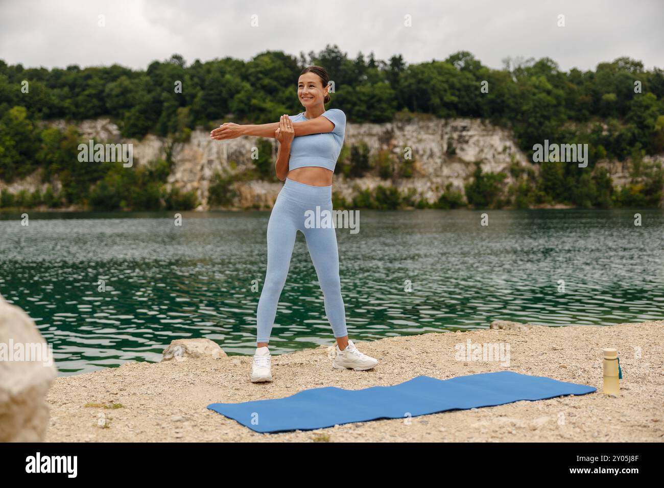 Une femme s'engage dans l'exercice en plein air près d'un beau lac, habillée d'un élégant équipement d'entraînement Banque D'Images