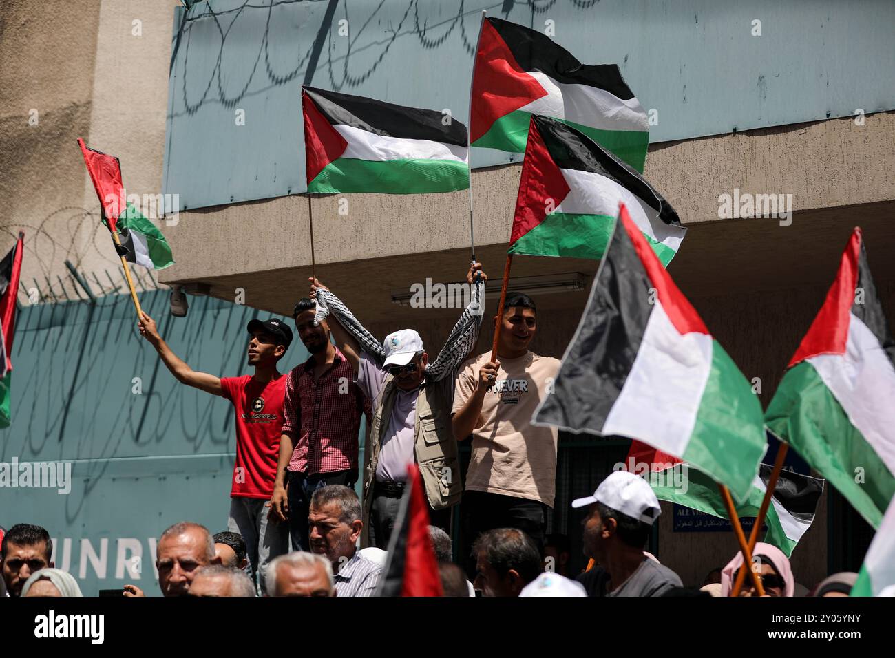 Gaza, Palestine. 21 juin 2023. Les Palestiniens tiennent des banderoles et brandissent le drapeau national palestinien lors d'une manifestation devant le siège de l'Office de secours et de travaux des Nations Unies pour les réfugiés de Palestine (UNRWA) à Gaza, alors que l'aide alimentaire et les services de base aux Palestiniens à Gaza sont réduits. L'événement a coïncidé avec la convocation de la Commission consultative (AdCom) sur l'UNRWA à Beyrouth, au cours de laquelle la situation financière difficile de l'agence des Nations Unies a été mise en évidence ainsi que la menace qui en découle pour la fourniture de nourriture et de services de base aux réfugiés palestiniens dans la région Banque D'Images