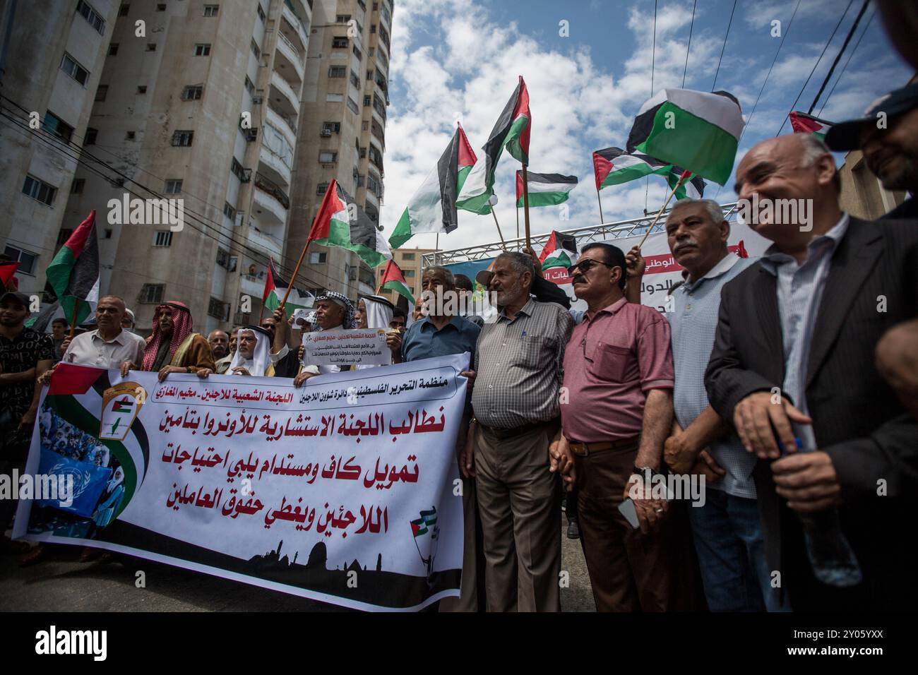 Gaza, Palestine. 21 juin 2023. Les Palestiniens tiennent des banderoles et brandissent le drapeau national palestinien lors d'une manifestation devant le siège de l'Office de secours et de travaux des Nations Unies pour les réfugiés de Palestine (UNRWA) à Gaza, alors que l'aide alimentaire et les services de base aux Palestiniens à Gaza sont réduits. L'événement a coïncidé avec la convocation de la Commission consultative (AdCom) sur l'UNRWA à Beyrouth, au cours de laquelle la situation financière difficile de l'agence des Nations Unies a été mise en évidence ainsi que la menace qui en découle pour la fourniture de nourriture et de services de base aux réfugiés palestiniens dans la région Banque D'Images