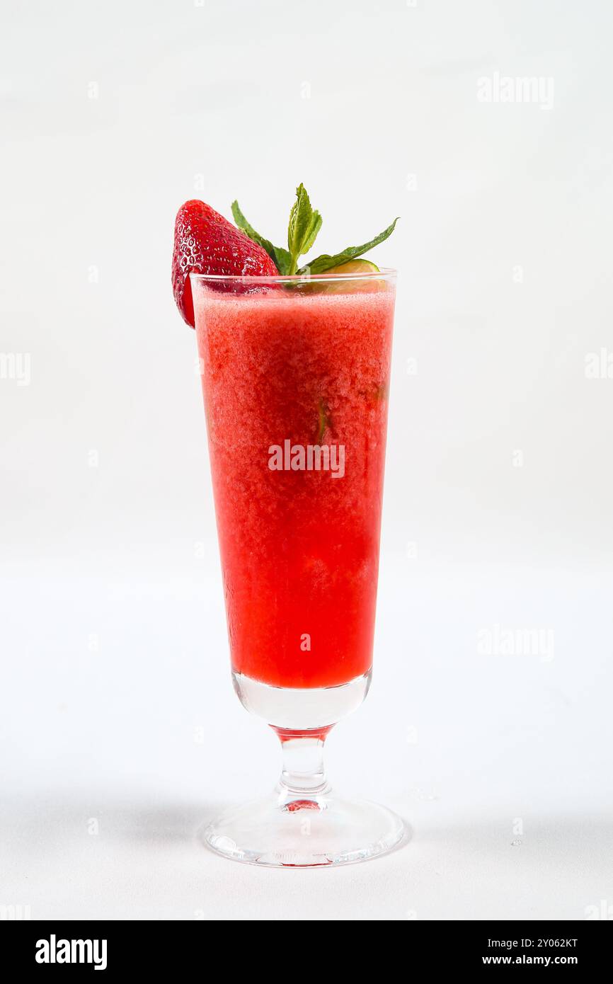 Un grand verre avec des boissons roses ou des boissons de fraises rouges juteuses et fraîches sur fond blanc. Banque D'Images