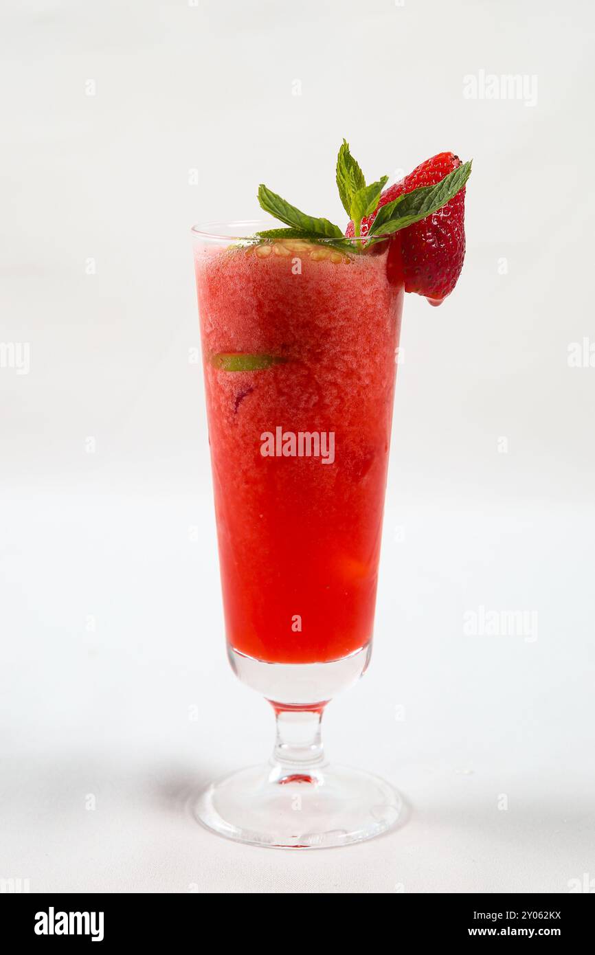 Un grand verre avec des boissons roses ou des boissons de fraises rouges juteuses et fraîches sur fond blanc. Banque D'Images