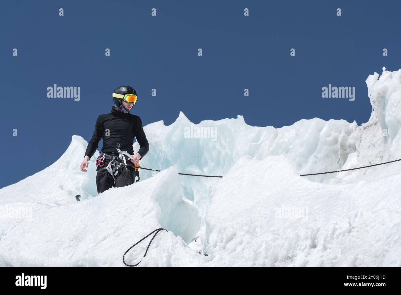 Un alpiniste professionnel portant un casque et un masque de ski sur l'assurance entaille la hache de glace dans le glacier. Le travail d'un grimpeur professionnel en Winte Banque D'Images