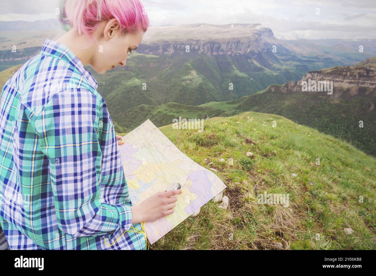 Voyageuse fille avec des cheveux multicolores assis sur la carte de lecture de la nature et tenant une boussole à la main. Le concept de navigation dans la recherche et le tourisme i Banque D'Images