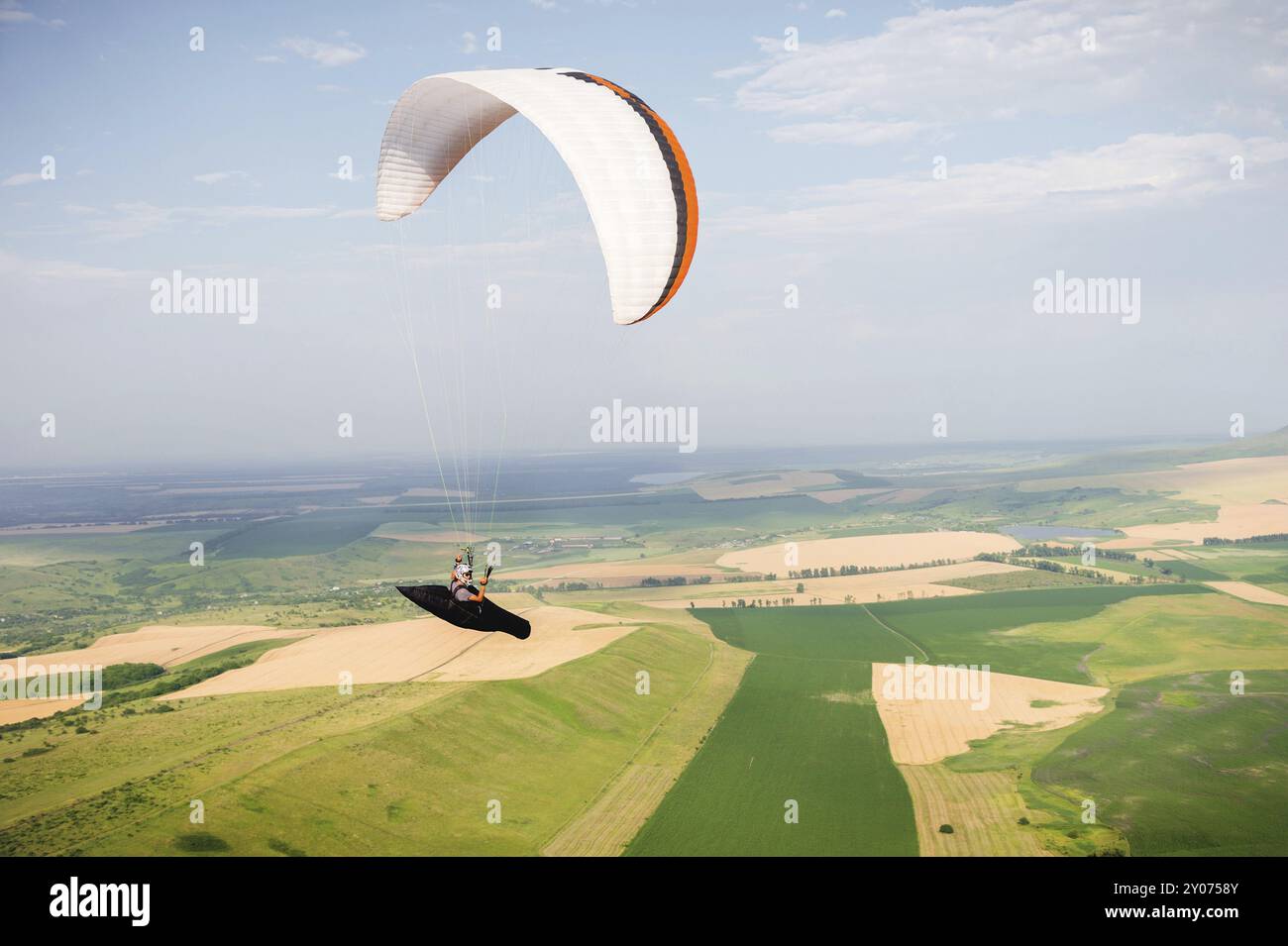 Un parapente professionnel dans un cocon suit des mouches au-dessus du sol contre le ciel et les champs Banque D'Images Un parapente professionnel dans un cocon suit des mouches au-dessus du sol contre le ciel et les champs Banque D'Images