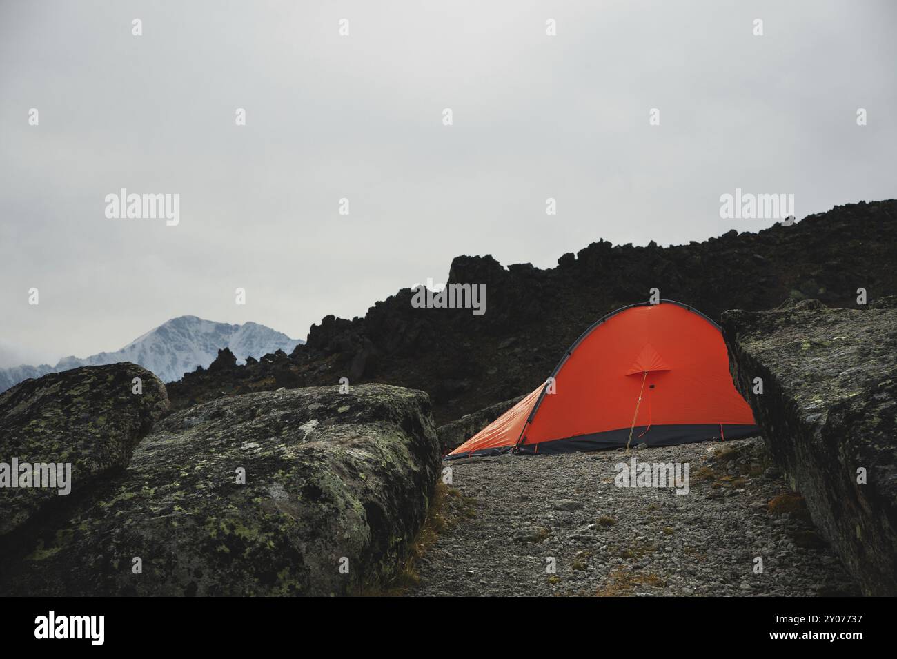 Une tente orange se dresse haut dans les montagnes entre deux hauts rochers appelés champignons de pierre dans le Caucase. Montagne Elbrus Banque D'Images