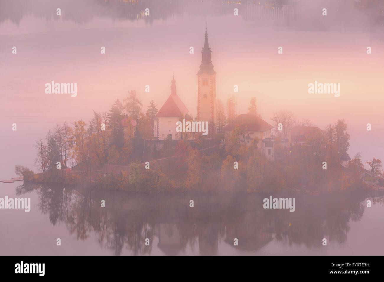 Vue aérienne du matin au lever du soleil sur le lac Bled avec l'église Saint-Marys, la Slovénie dans le brouillard et les arbres d'automne Banque D'Images