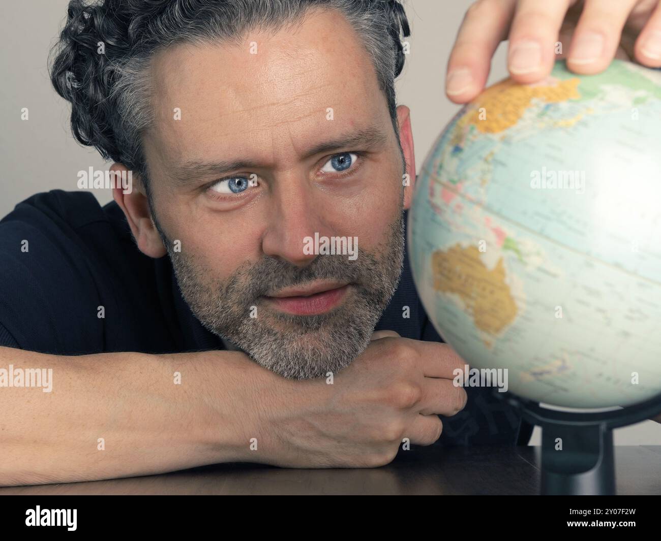 Bel homme à la recherche d'un petit monde pour trouver la prochaine destination de voyage Banque D'Images