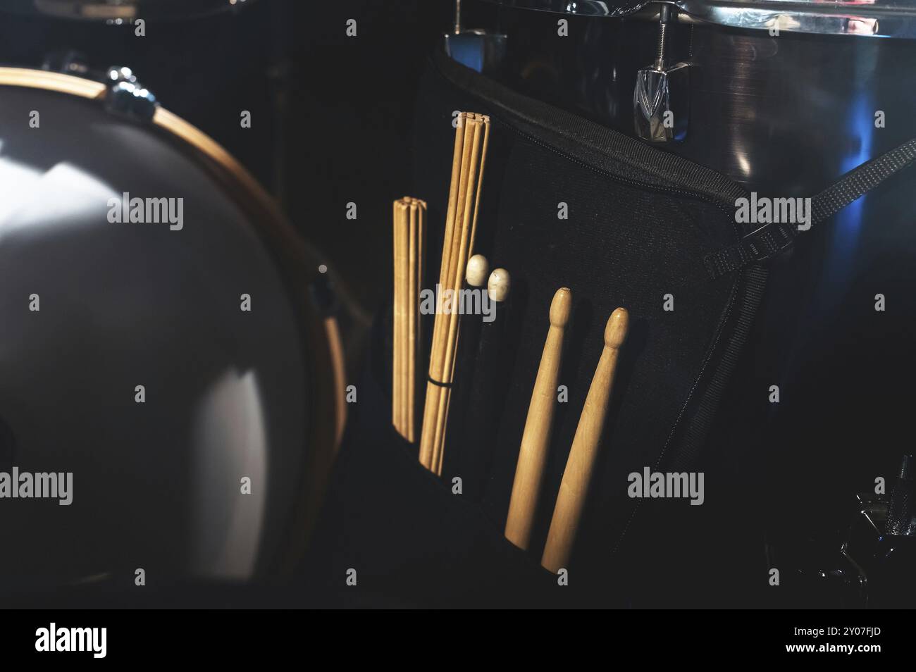 Gros plan de bâtons de tambour dans un boîtier sur l'un des tambours dans un studio sombre. Le concept des spectacles en direct Banque D'Images