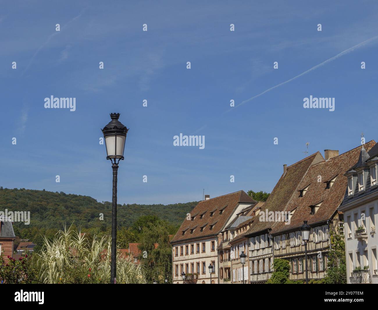 Simple lampadaire devant une rangée pittoresque de maisons et paysage verdoyant sous un ciel bleu, Weissenburg, Alsace, France, Europe Banque D'Images