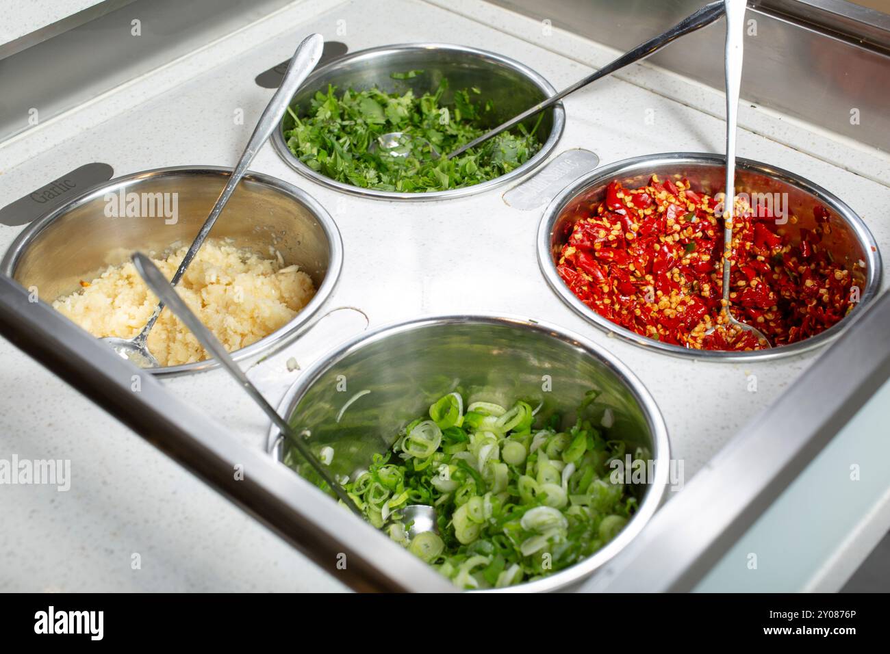Une vue sur un bar à condiments, avec des contenants pour l'ail, l'échalote, le piment rouge et la coriandre, vu dans un restaurant local. Banque D'Images