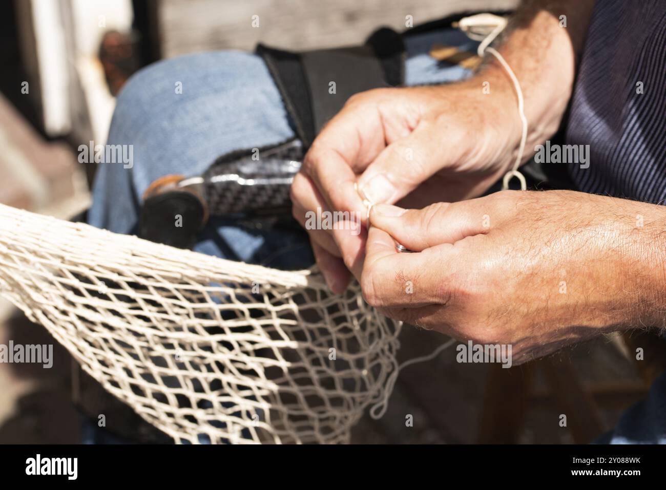 Enkhuizen, pays-Bas. Juin 2022. Les mains d'un pêcheur réparant les filets de pêche avec aiguille et fil. Gros plan Banque D'Images