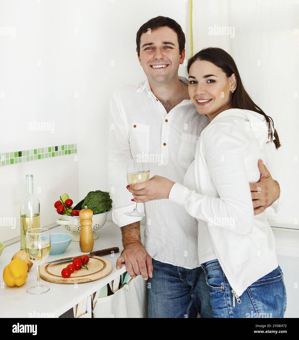 Portrait d'un couple heureux préparant de la nourriture et buvant du vin blanc dans la cuisine Banque D'Images