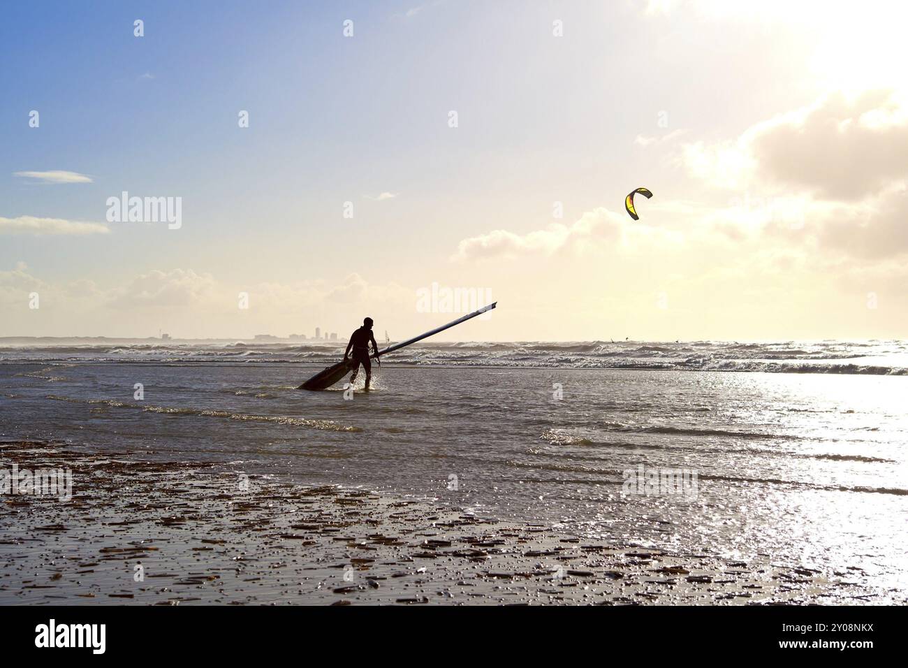 Kitesurfer contre le soleil sur la plage dans les vagues Banque D'Images